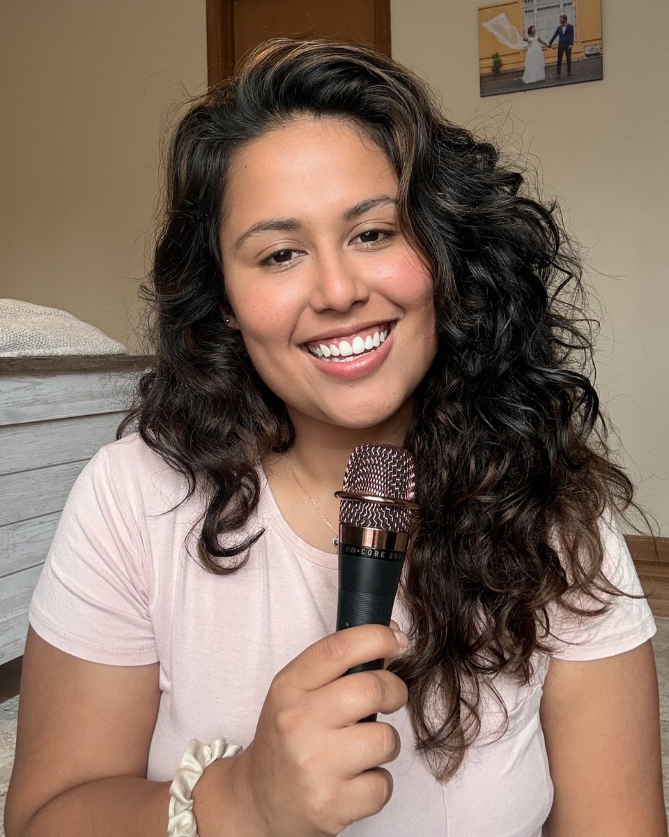 Lala sonriendo con un micrófono en la mano
