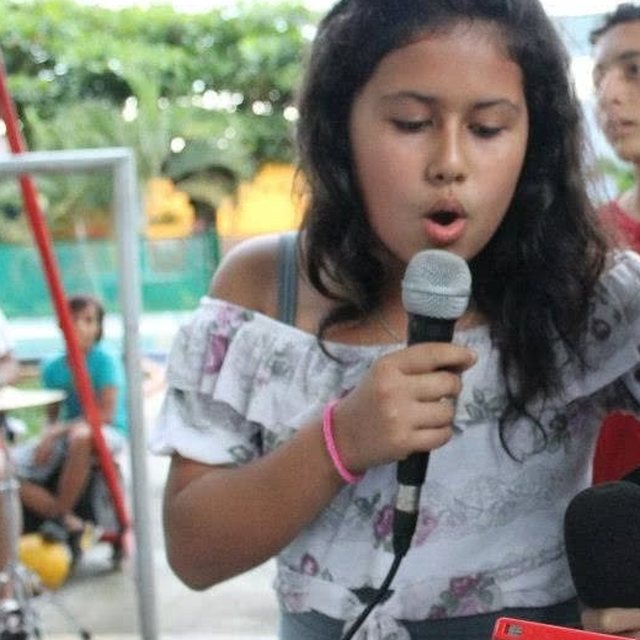 Lala de niña cantando con un micrófono